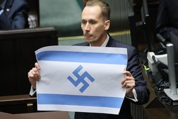 Un diputado polaco de derecha radical muestra en el parlamento la bandera israelí con la esvástica nazi